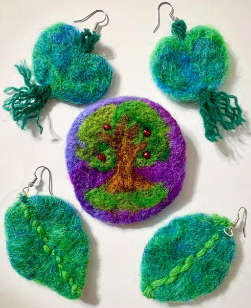 Some plant-themed earrings and a broach, made of felted colored wool.